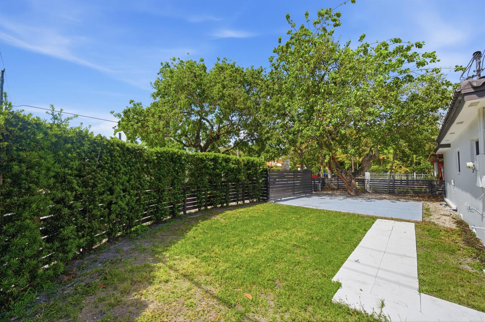 A grassy backyard features a concrete patio, a privacy fence, and a large tree — 1770 SW 17th Avenue, Miami FL 33145, MIAMI, FL