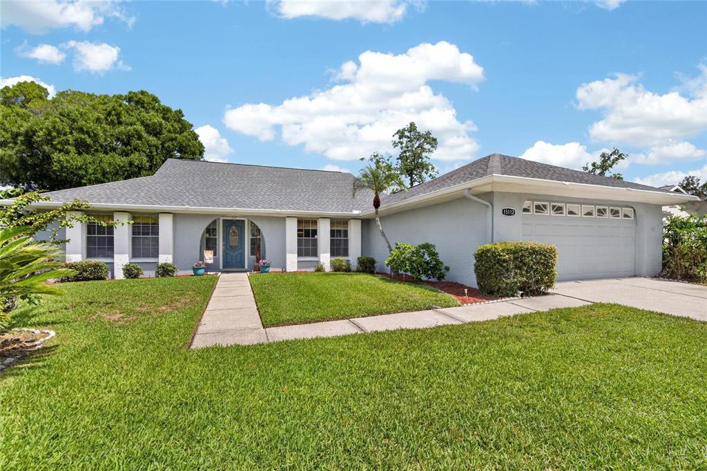 A single-story gray house with a two-car garage and a front walkway — 15112 ROUNDUP DRIVE, TAMPA, FL