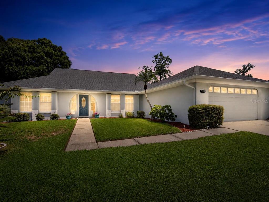 A single-story house with a gray roof, white stucco exterior, and a two-car garage — 15112 ROUNDUP DRIVE, TAMPA, FL
