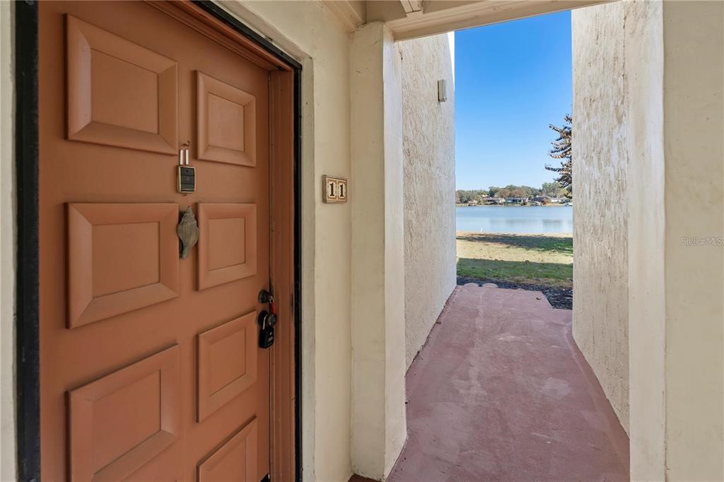 A brown front door with a seashell knocker sits beside an outdoor walkway overlooking water — 530 ORANGE DRIVE UNIT 11, ALTAMONTE SPRINGS, FL