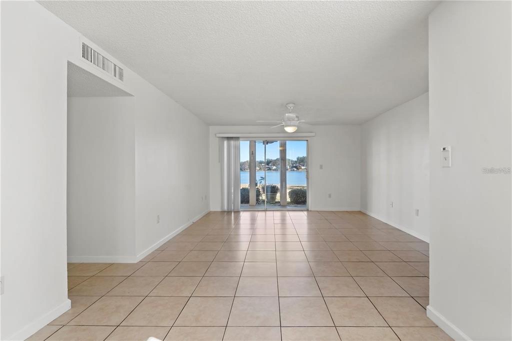 An empty room with beige tile flooring, white walls, and a sliding glass door view — 530 ORANGE DRIVE UNIT 11, ALTAMONTE SPRINGS, FL