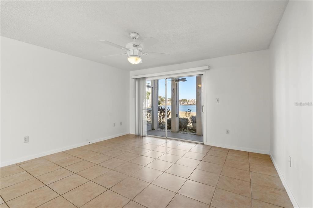 An empty room with beige tile flooring, a ceiling fan, and sliding glass doors to a patio — 530 ORANGE DRIVE UNIT 11, ALTAMONTE SPRINGS, FL