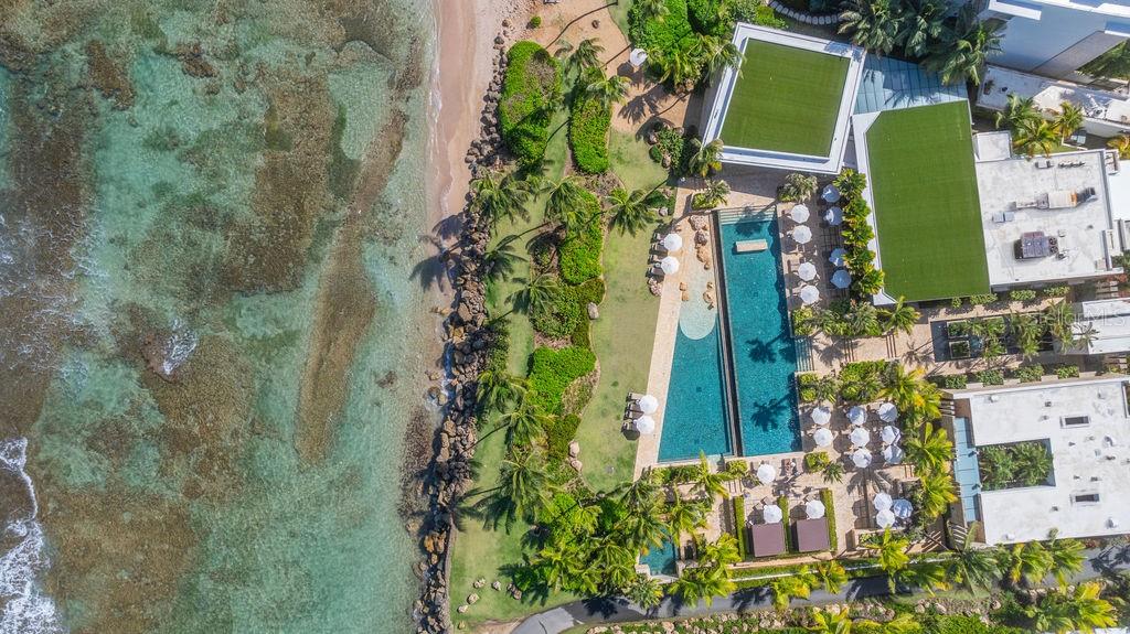 An aerial view shows a coastal resort with a long swimming pool and lush landscaping — 200 Dorado Beach Dr WEST BEACH PH UNIT 3141-3142, DORADO, PR