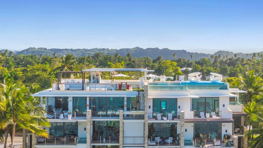 An exterior view of a modern multi-story building featuring balconies and a rooftop infinity pool — 200 Dorado Beach Dr WEST BEACH PH UNIT 3141-3142, DORADO, PR