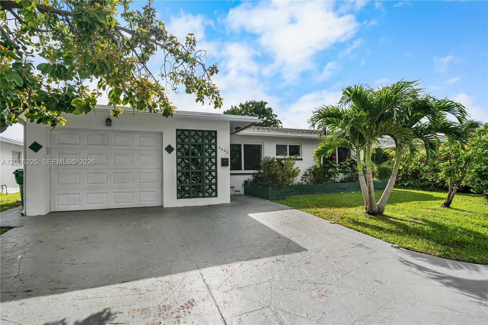 A white single-story house features a garage, a decorative screen wall, and a palm tree — 4402 NW 44th Ave, Tamarac FL 33319, TAMARAC, FL