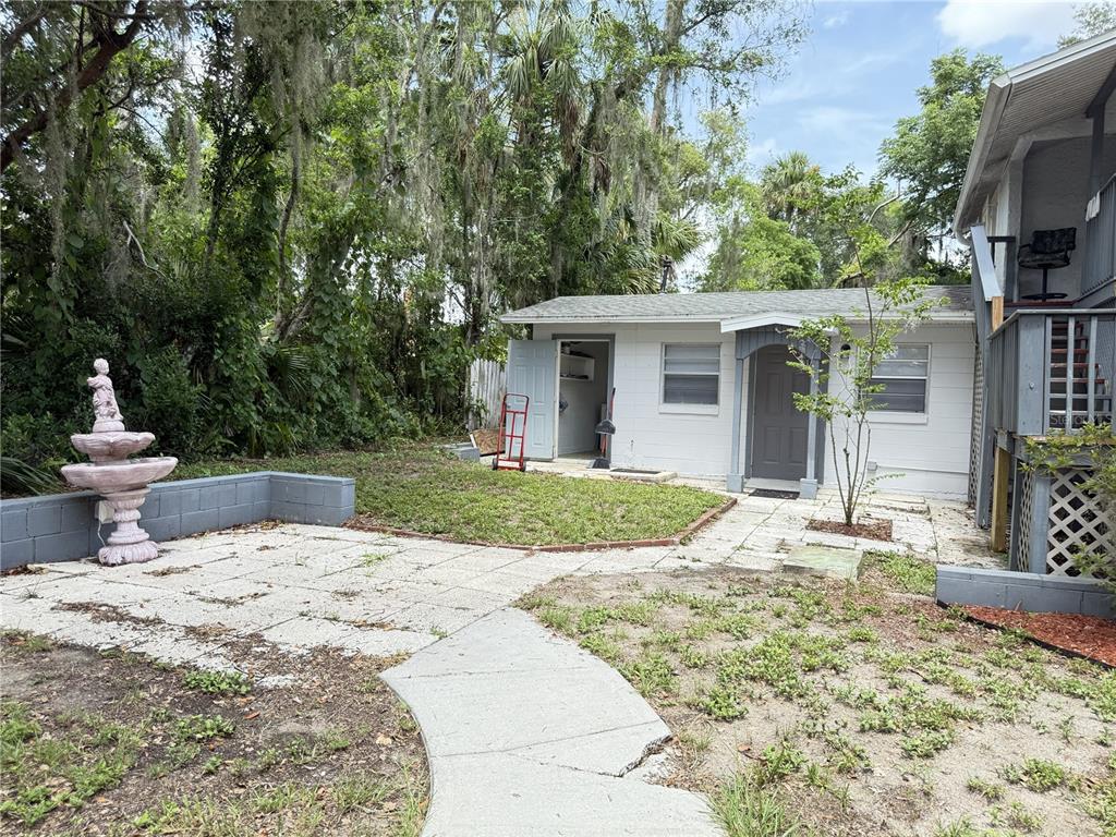 A backyard features a concrete patio, a small white building, and a decorative fountain — 123 S ARLINGTON AVENUE UNIT C, DELAND, FL