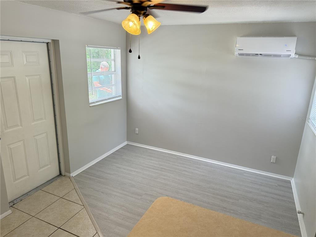 A room with light gray walls, wood-look flooring, a ceiling fan, and a wall-mounted air conditioner — 123 S ARLINGTON AVENUE UNIT C, DELAND, FL