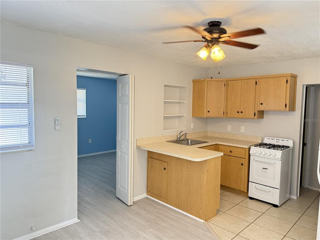 A kitchen features light wood cabinets, a white stove, and a breakfast bar peninsula — 123 S ARLINGTON AVENUE UNIT C, DELAND, FL