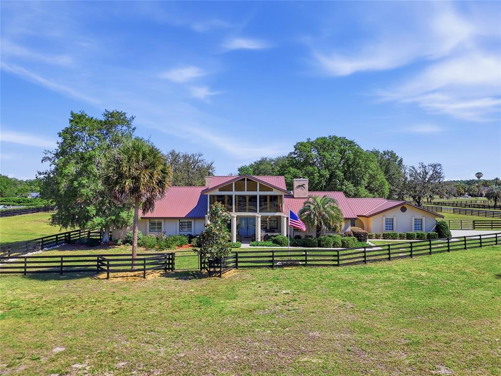 A large, single-story house with a metal roof and a central two-story glass facade — 9700 SW 67TH TERRACE, OCALA, FL