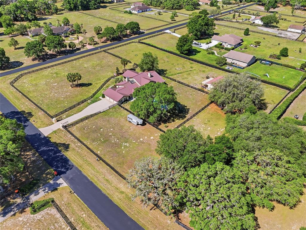 An aerial view shows a house with a metal roof surrounded by fenced pastures — 9700 SW 67TH TERRACE, OCALA, FL