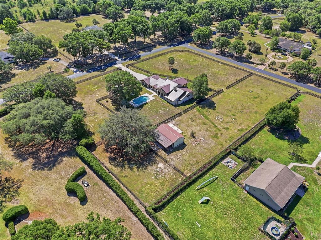 An aerial view shows a house with a pool, a detached garage, and fenced pastures — 9700 SW 67TH TERRACE, OCALA, FL