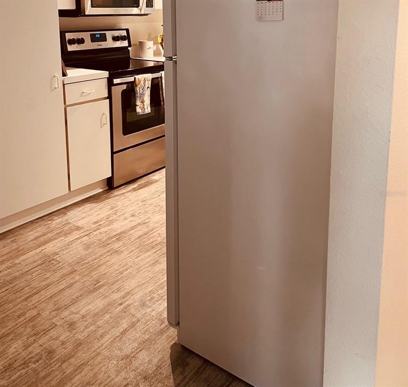 A white refrigerator stands in the foreground next to a kitchen with stainless steel appliances — 9300 CLUBSIDE CIRCLE UNIT 1109, SARASOTA, FL