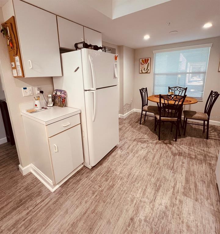 A kitchen with white cabinets and appliances next to a dining area with a table — 9300 CLUBSIDE CIRCLE UNIT 1109, SARASOTA, FL