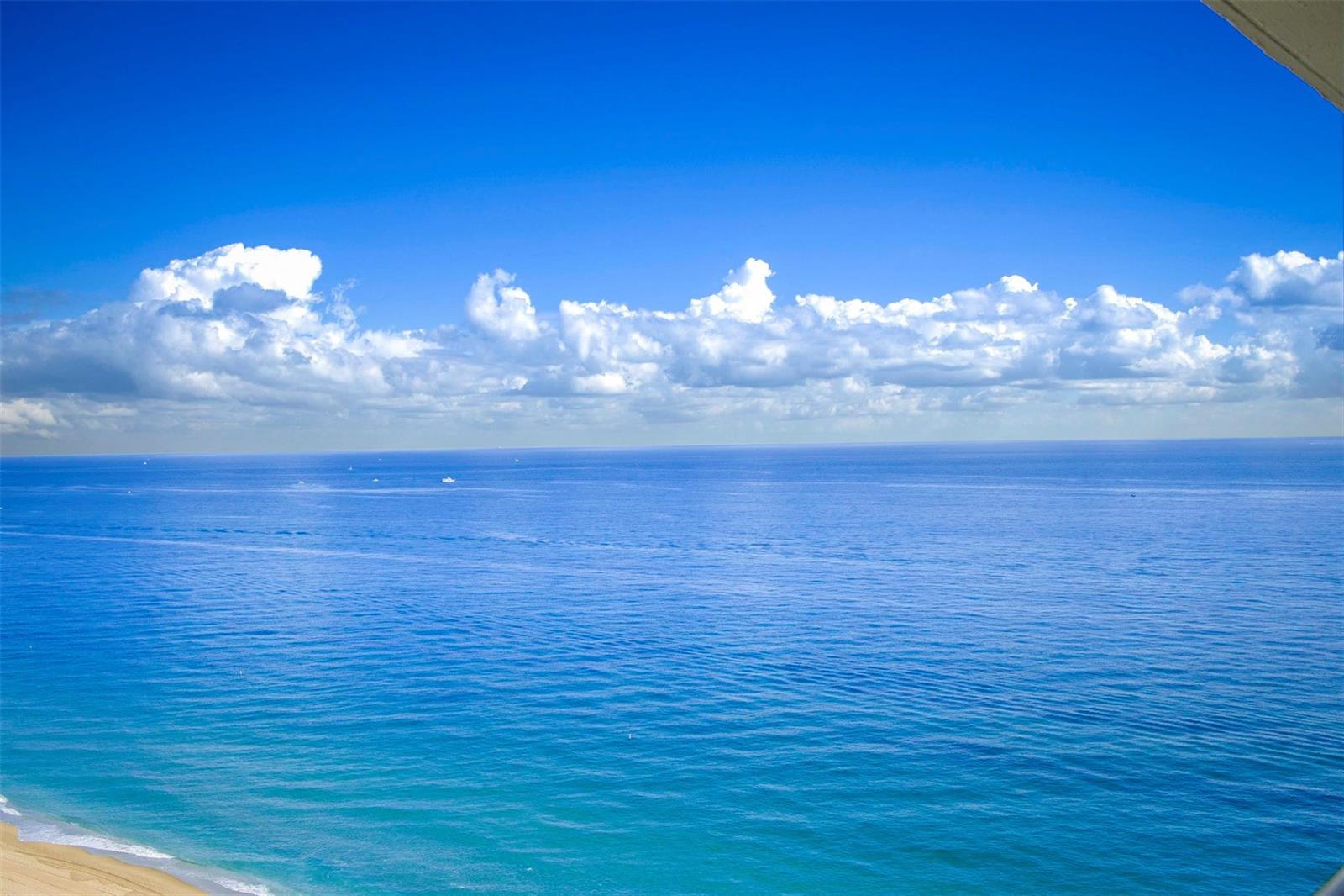 A high-angle view of the ocean and beach under a bright blue sky — POMPANO BEACH, FL