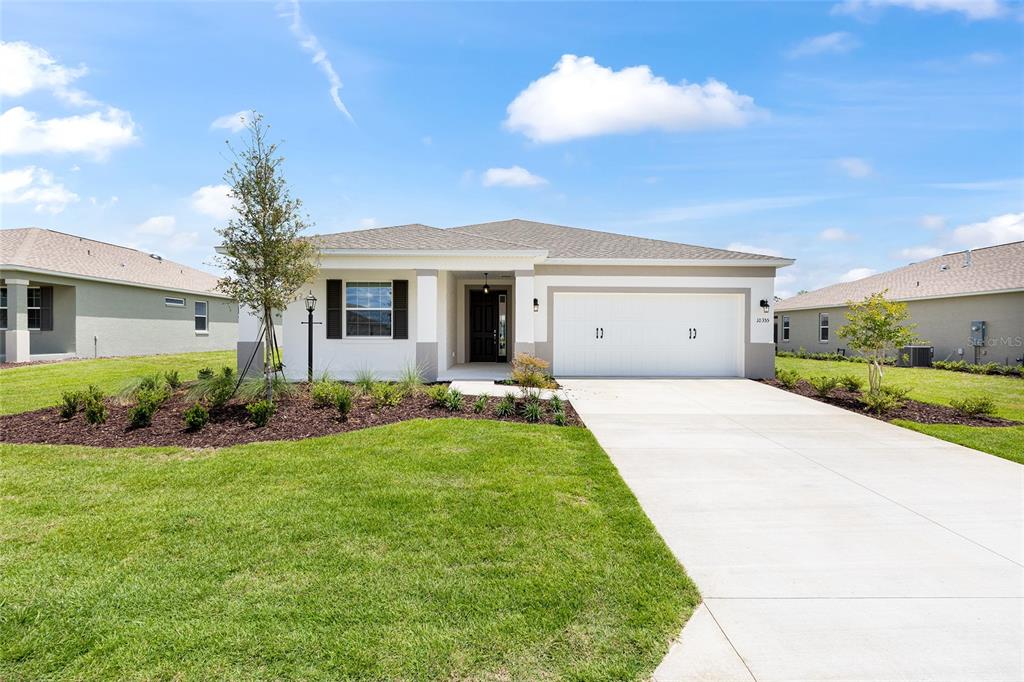 A single-story suburban house with a white exterior, two-car garage, and a landscaped front yard — 10355 SW 105TH TERRACE, OCALA, FL
