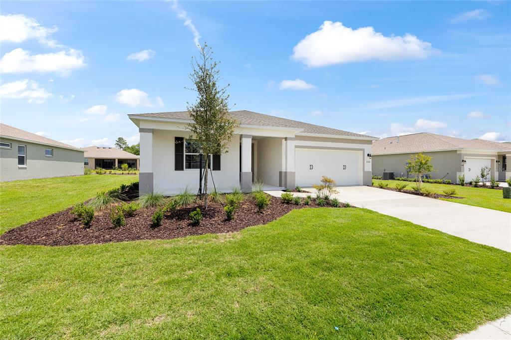 A single-story suburban house with a white stucco exterior, two-car garage, and landscaped front yard — 10355 SW 105TH TERRACE, OCALA, FL