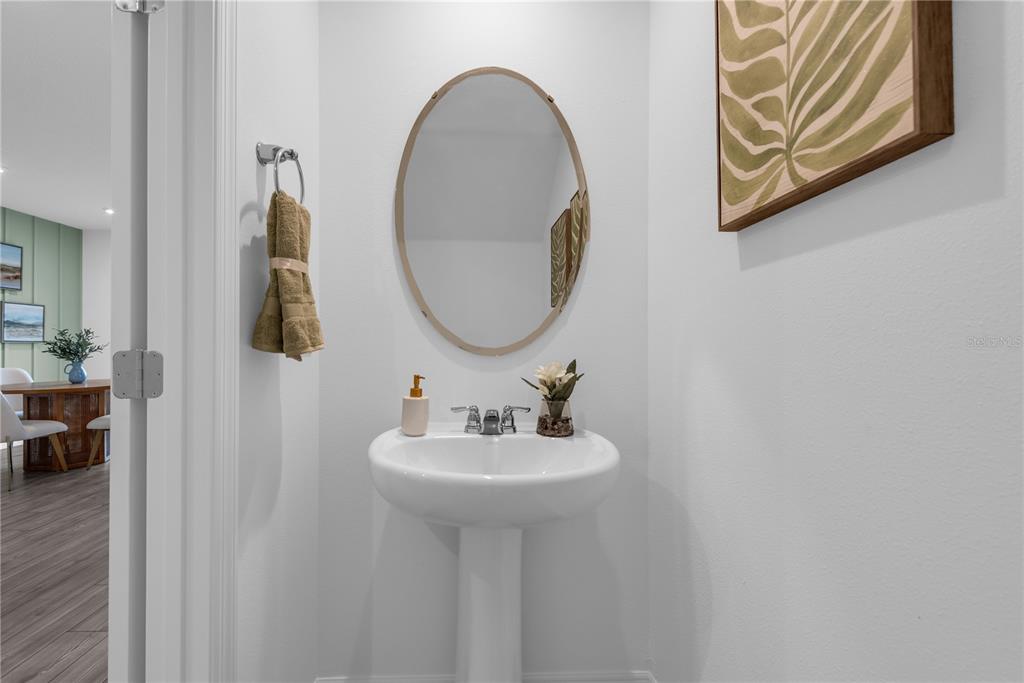 A half bathroom features a white pedestal sink, an oval mirror, and a framed leaf print — 218 CUBAN ROYAL PALM WAY, DAVENPORT, FL