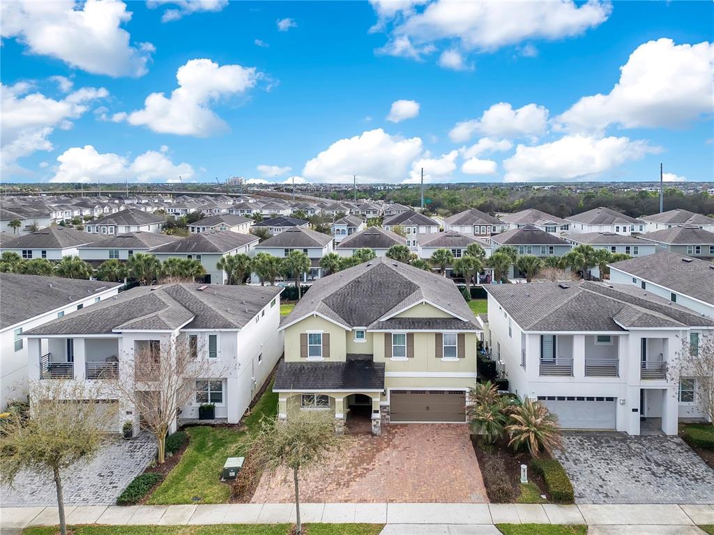 An aerial view shows a two-story light green house centered between two white modern homes — 210 BURMA STREET, KISSIMMEE, FL