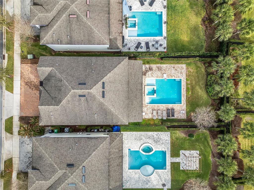 An aerial view shows three suburban houses with swimming pools and landscaped backyards — 210 BURMA STREET, KISSIMMEE, FL