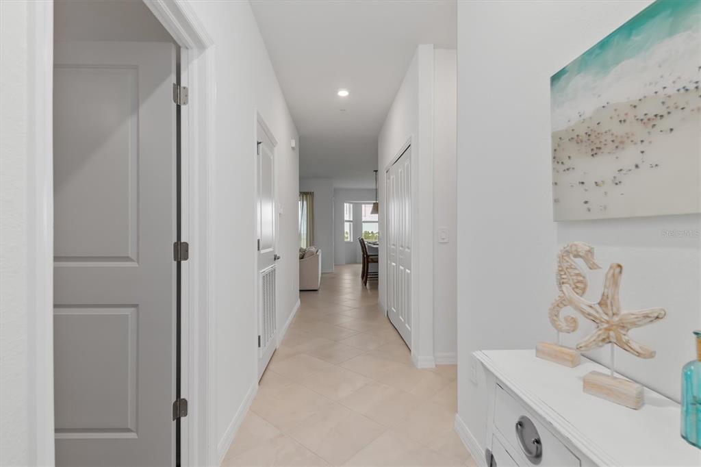 A hallway with light tile flooring leads toward a dining area and living space — 17625 OPAL SAND DRIVE UNIT 401, VENICE, FL