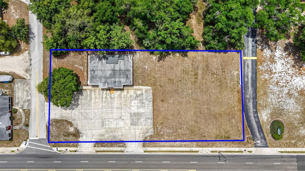 An aerial view shows a rectangular lot with a building, paved parking, and surrounding trees — 2501 SOUTH STREET, LEESBURG, FL