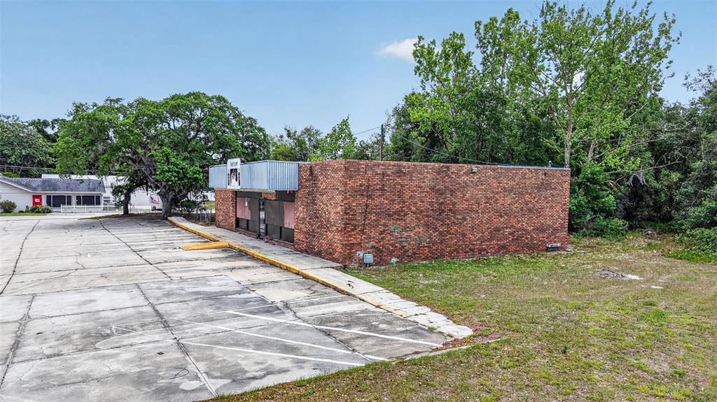 A single-story brick commercial building sits next to a large, cracked concrete parking lot — 2501 SOUTH STREET, LEESBURG, FL