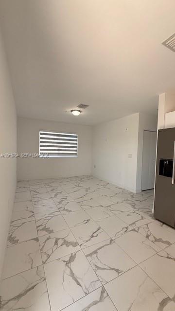 An empty room features white marble-patterned tile flooring, white walls, and a window with blinds — 811 E 52nd St # 102, Hialeah FL 33013, HIALEAH, FL