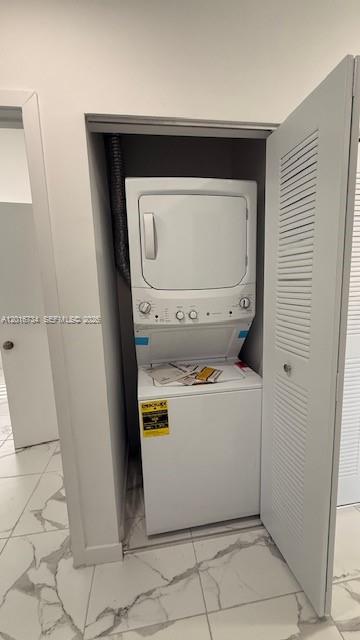 A white stacked washer and dryer unit is installed inside a closet with louvered doors — 811 E 52nd St # 102, Hialeah FL 33013, HIALEAH, FL
