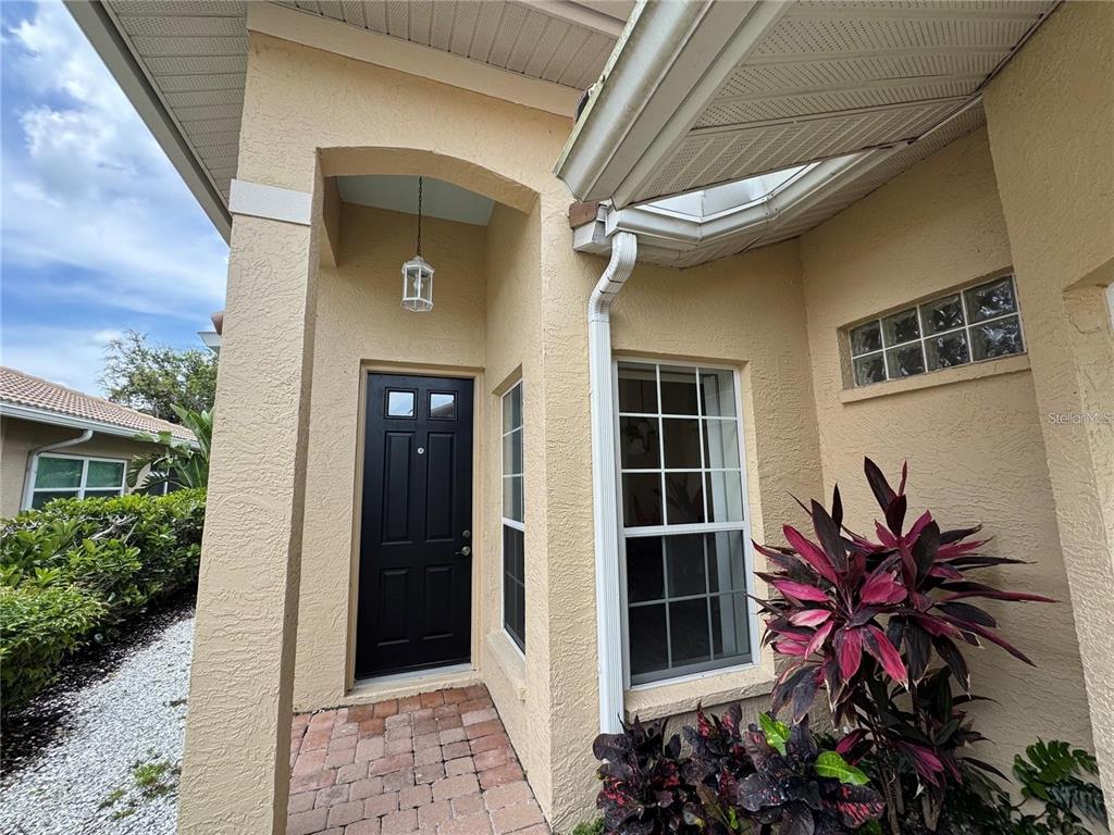 The exterior entrance features a black front door, a brick walkway, and a large plant — 315 AUBURN WOODS CIRCLE, VENICE, FL