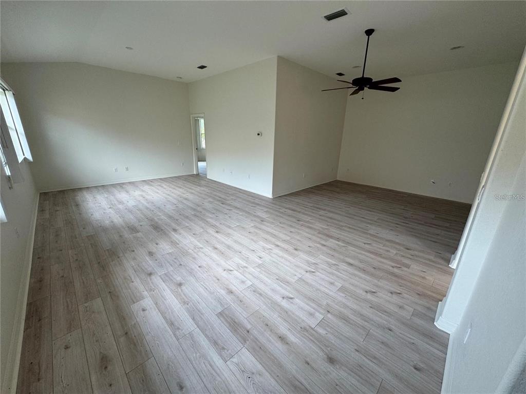 An empty room features light wood-look flooring, white walls, and a ceiling fan — 315 AUBURN WOODS CIRCLE, VENICE, FL