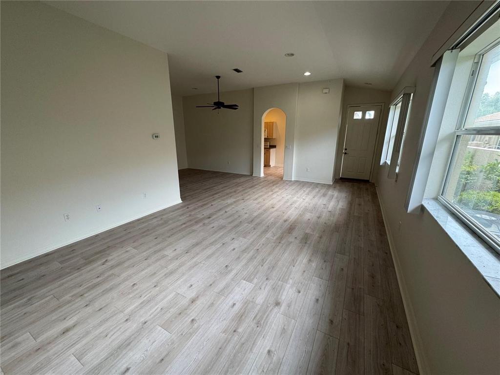 An open-concept living area features light wood-look flooring, a ceiling fan, and an arched doorway — 315 AUBURN WOODS CIRCLE, VENICE, FL