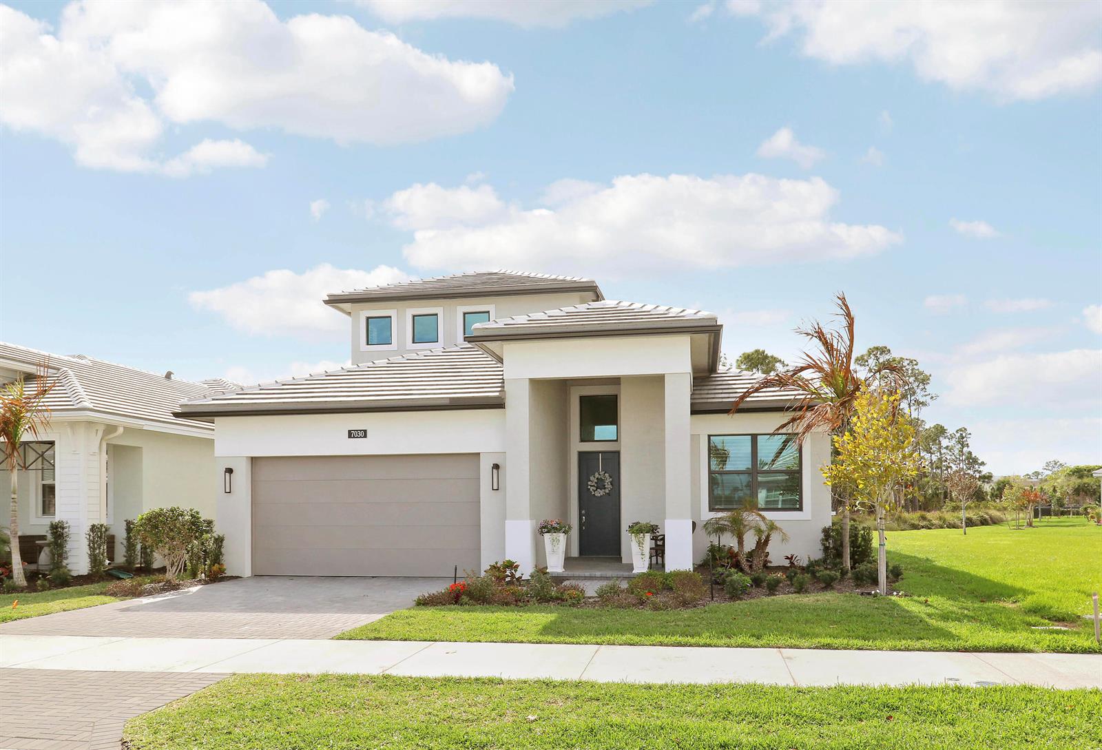 A modern white kitchen features a large quartz island with gold-accented bar stools — 7030 SE Haven Lane, Stuart FL 34997, STUART, FL