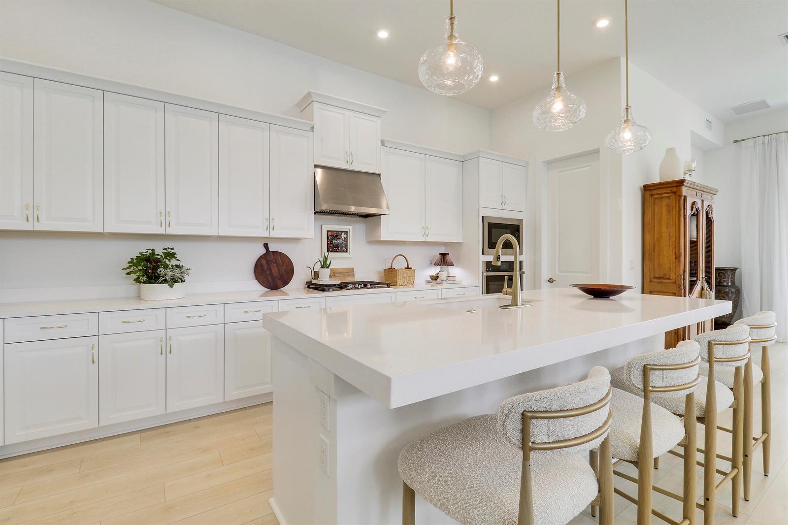An open-concept living and dining area features white furniture, a crystal chandelier, and light flooring — 7030 SE Haven Lane, Stuart FL 34997, STUART, FL