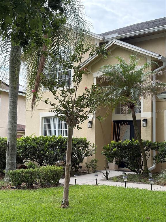 A two-story house exterior with a front walkway, landscaping, and a small tree in front — 8040 SOLITAIRE COURT, ORLANDO, FL