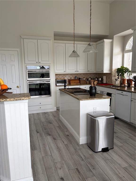A kitchen features white cabinetry, granite countertops, stainless steel appliances, and gray wood-look flooring — 8040 SOLITAIRE COURT, ORLANDO, FL