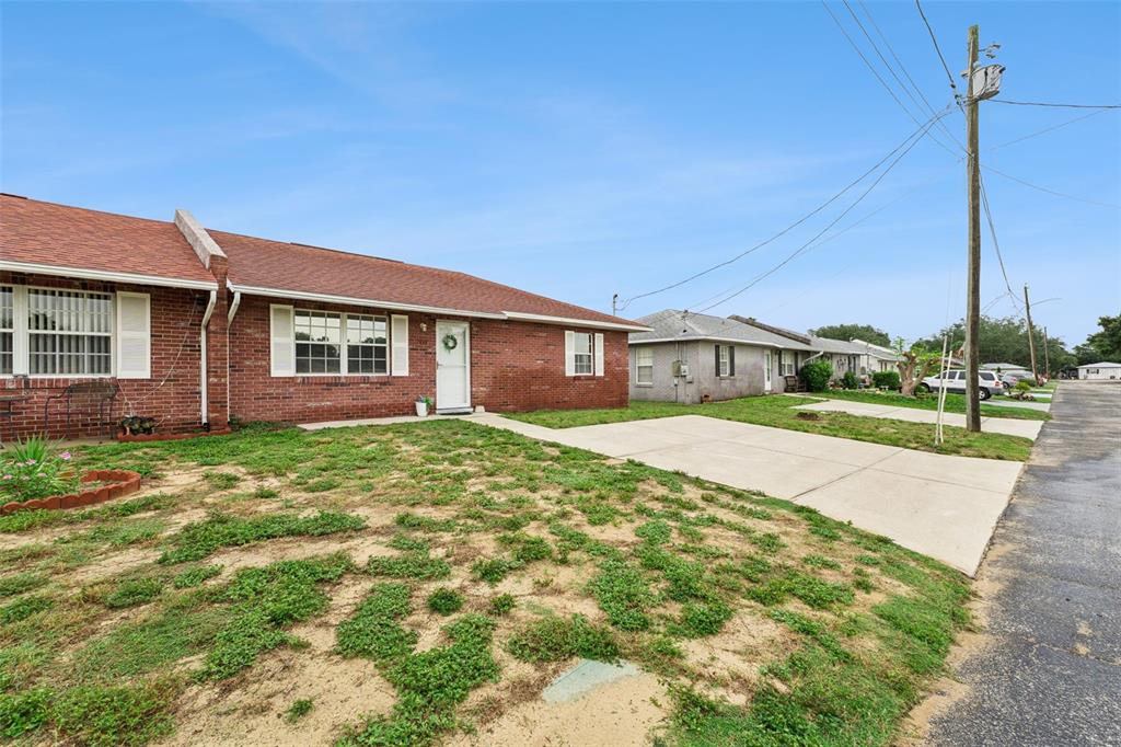 A red brick single-story duplex with a concrete driveway and a sparse grassy yard — 1433 THOUSAND ROSES AVENUE W, LAKE WALES, FL
