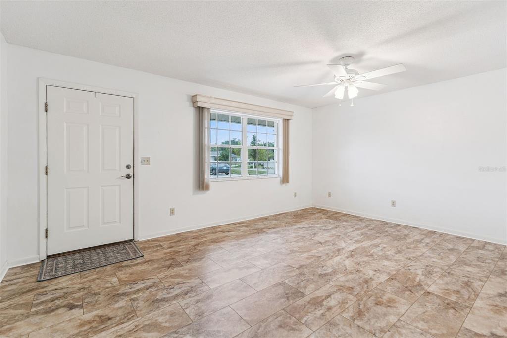 An empty room features white walls, a ceiling fan, a window, and tiled flooring — 1433 THOUSAND ROSES AVENUE W, LAKE WALES, FL