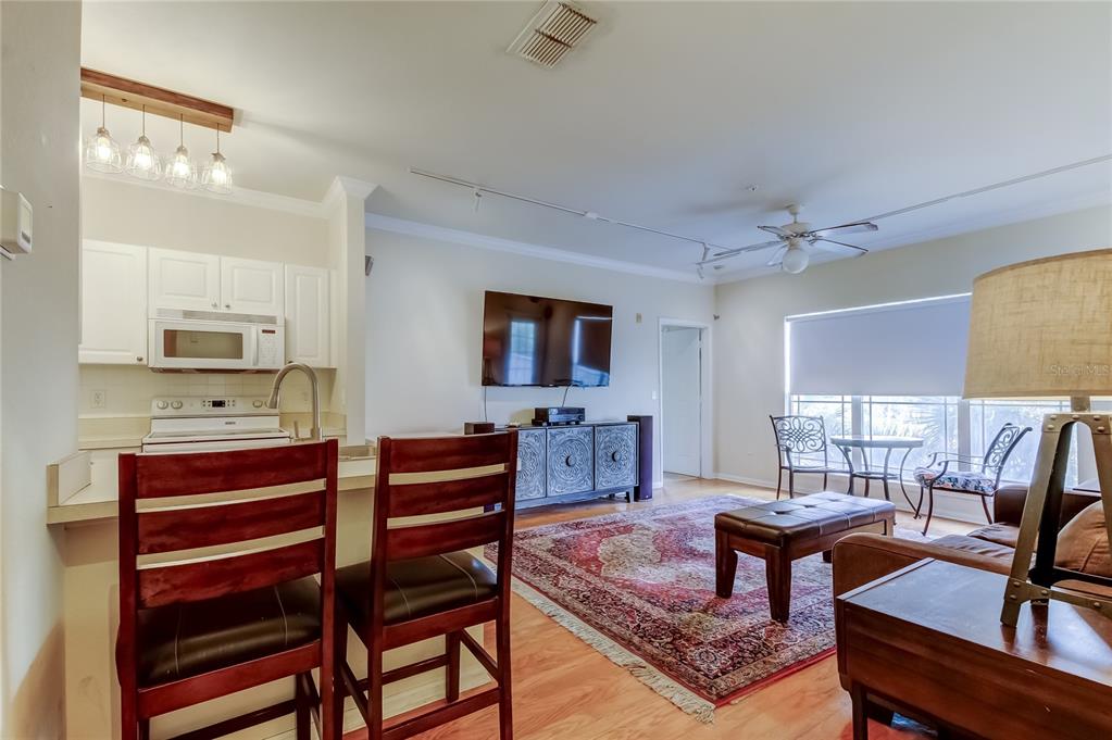 An open-concept living room and kitchen area with wood flooring and a large area rug — 1216 S MISSOURI AVENUE UNIT 322, CLEARWATER, FL