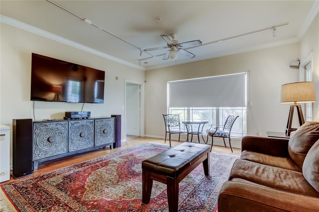 A living room features a large patterned rug, a leather sofa, and a decorative media console — 1216 S MISSOURI AVENUE UNIT 322, CLEARWATER, FL