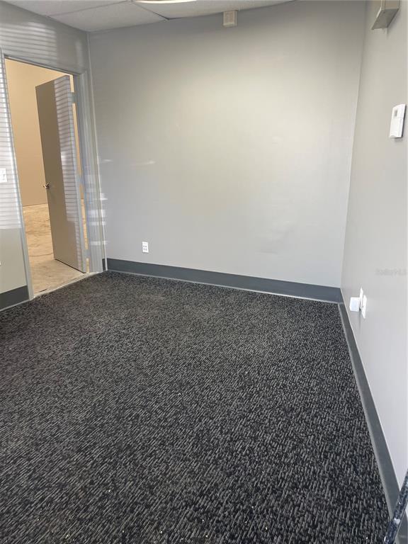 An empty office room features gray walls, dark gray carpet, and a doorway to another space — 5660 COMMERCE DRIVE UNIT 2, EDGEWOOD, FL