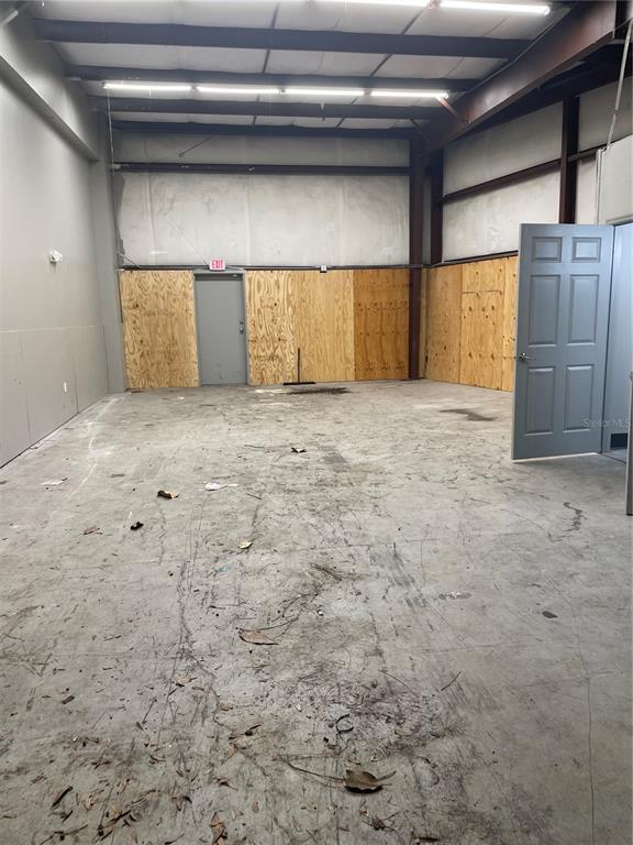An empty industrial warehouse space features concrete floors, exposed steel beams, and plywood wall panels — 5660 COMMERCE DRIVE UNIT 2, EDGEWOOD, FL