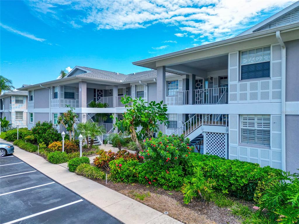 A two-story apartment building with a parking lot and landscaped garden in the foreground — 1145 EDGEWATER CIRCLE UNIT 1145, BRADENTON, FL
