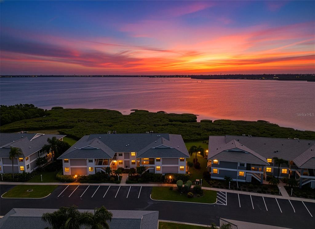 An aerial view of apartment buildings overlooking a large body of water at sunset — 1145 EDGEWATER CIRCLE UNIT 1145, BRADENTON, FL
