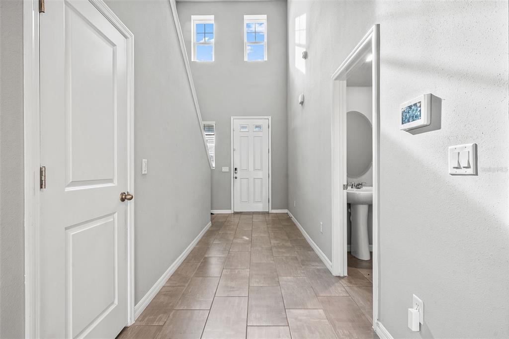 A tiled entryway features a white front door, high ceilings, and a small powder room — 3361 FRESNO PLACE, ZEPHYRHILLS, FL