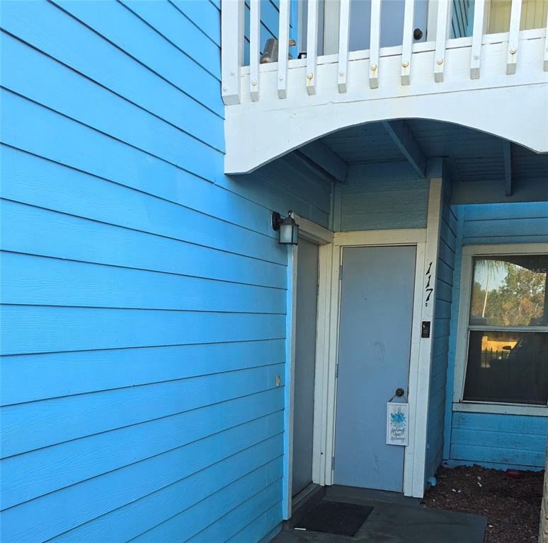 The exterior of a blue-sided building features a covered entryway with a door numbered 117 — 2729 N POINCIANA BOULEVARD UNIT 117, KISSIMMEE, FL
