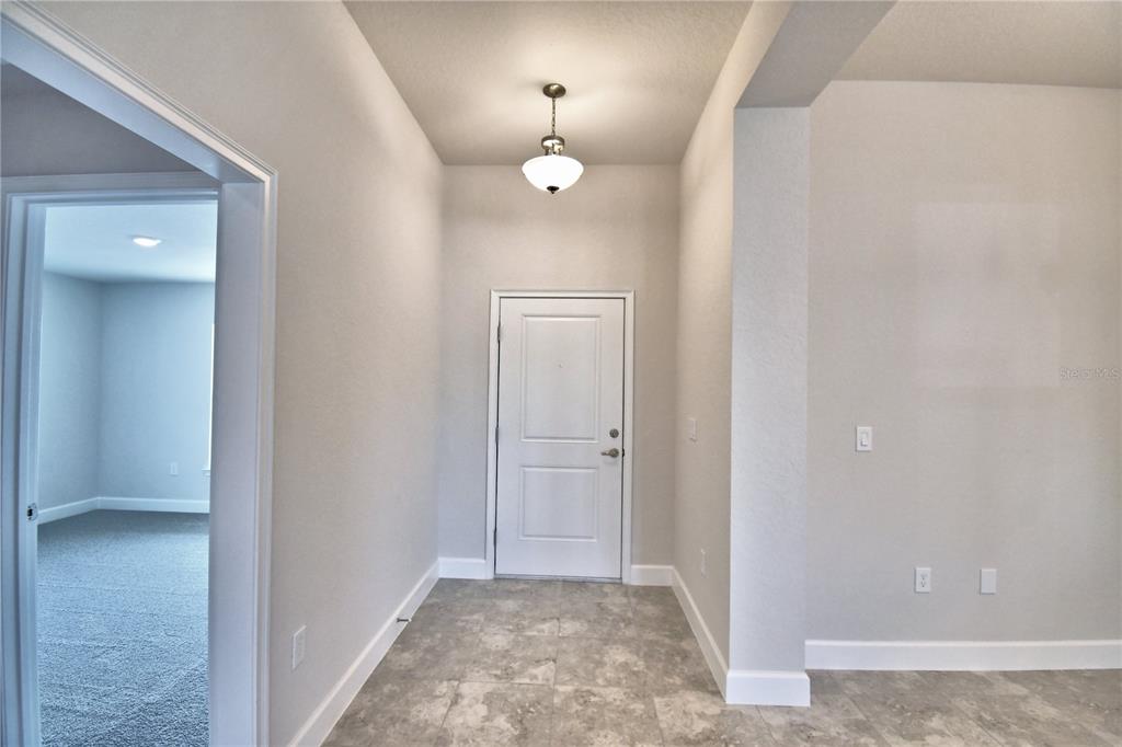 An entryway features a white door, tiled flooring, a pendant light, and an adjacent room — 4608 CALAMINT LANE, AUBURNDALE, FL