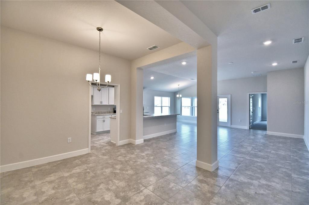 An open-concept living area features light gray tile flooring, white walls, and a dining chandelier — 4608 CALAMINT LANE, AUBURNDALE, FL
