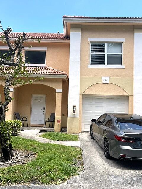 A two-story tan townhouse features a white front door, a garage, and a parked car — 717 Talia Circle, Palm Springs FL 33461, PALM SPRINGS, FL