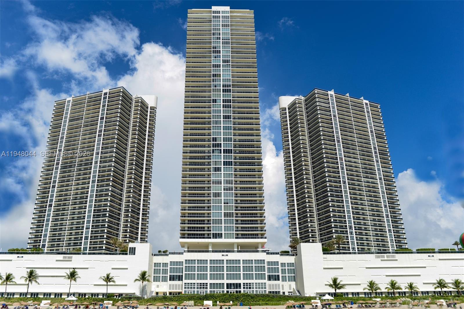 Three tall, modern residential towers rise above a low-rise podium near a sandy beach — 1800 S Ocean Dr # 3805, Hallandale Beach FL 33009, HALLANDALE BEACH, FL