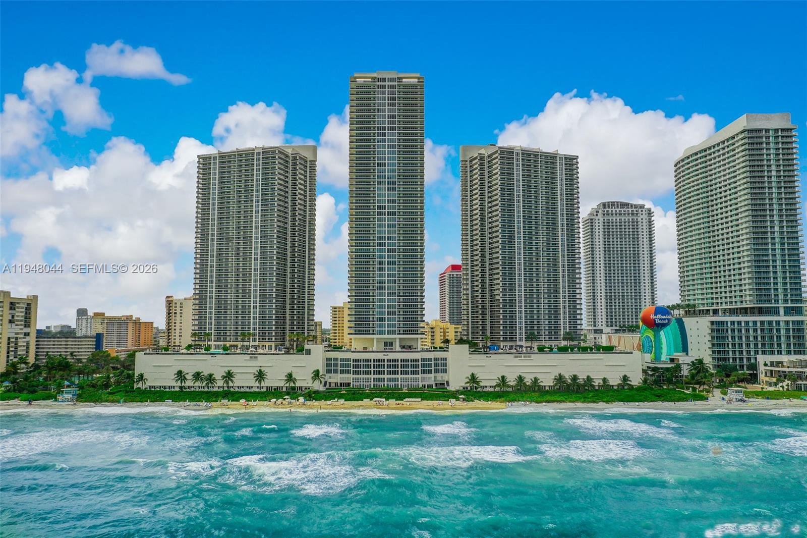 An aerial view shows high-rise residential towers situated directly along a sandy beach — 1800 S Ocean Dr # 3805, Hallandale Beach FL 33009, HALLANDALE BEACH, FL